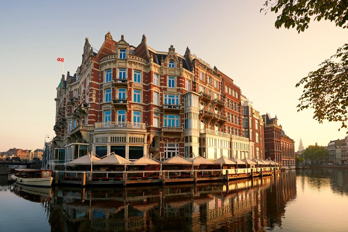 Amsterdam canal district at dusk — gabled 17th-century townhouses reflected in the Herengracht, bicycles on the bridge