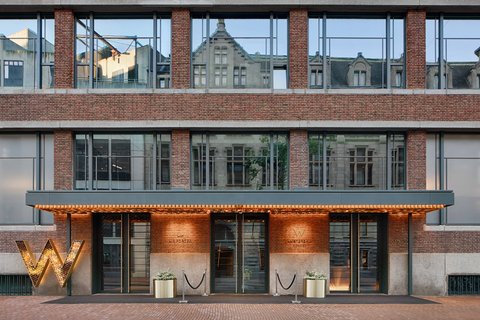 W Amsterdam — design hotel rooftop pool above Spuistraat with the Royal Palace and Dam Square skyline behind