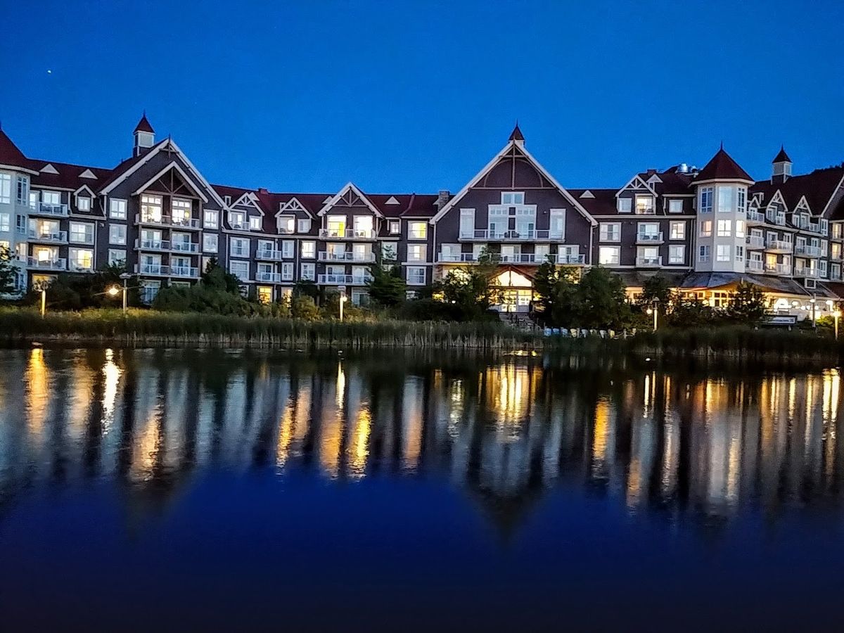 Blue Mountain Village at dusk — Ontario's largest ski resort with the Niagara Escarpment ridge above and Georgian Bay beyond