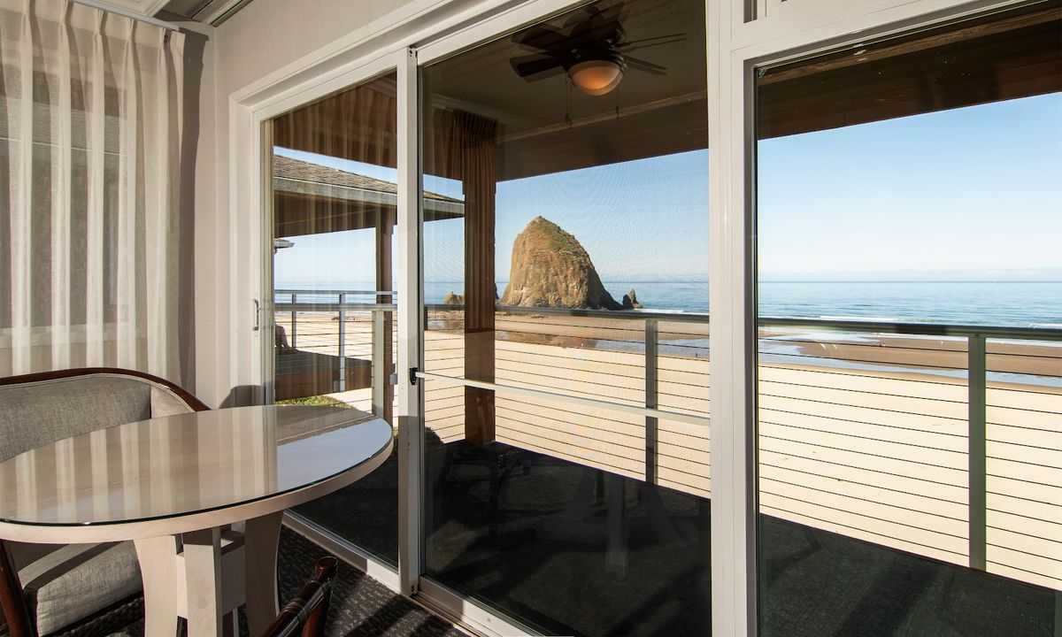 Cannon Beach, Oregon — Haystack Rock 235-foot sea stack at golden hour with Pacific surf and wide sandy beach