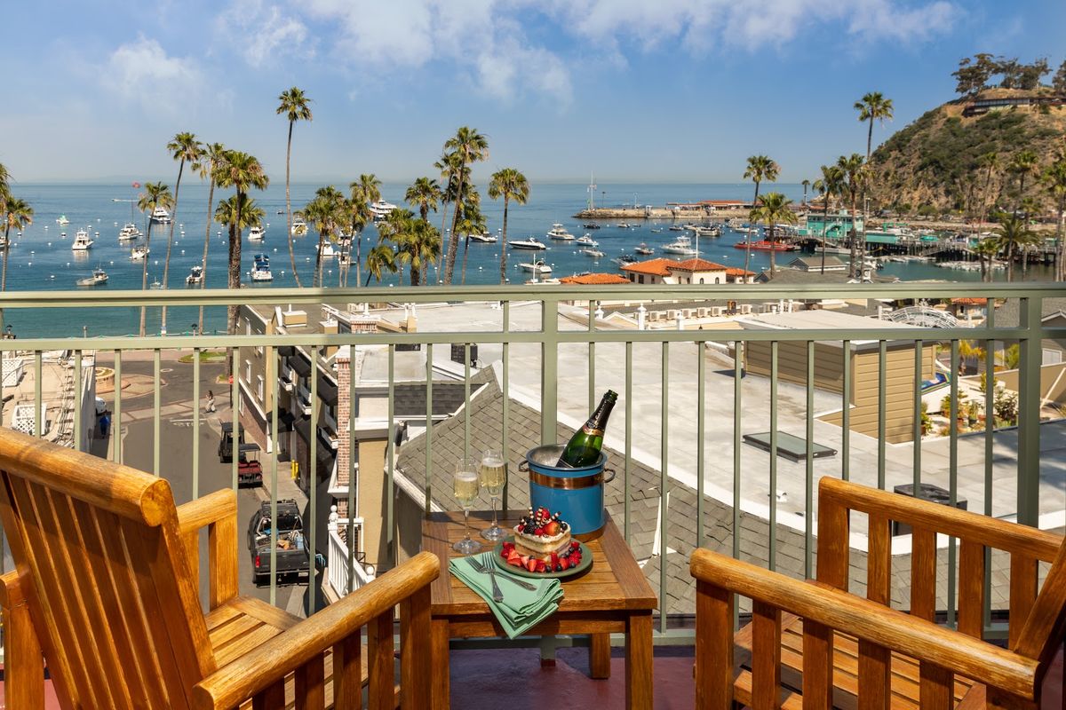 Catalina Island Avalon harbor at golden hour — the iconic Casino Building, palm-fringed waterfront, and yachts moored in turquoise water