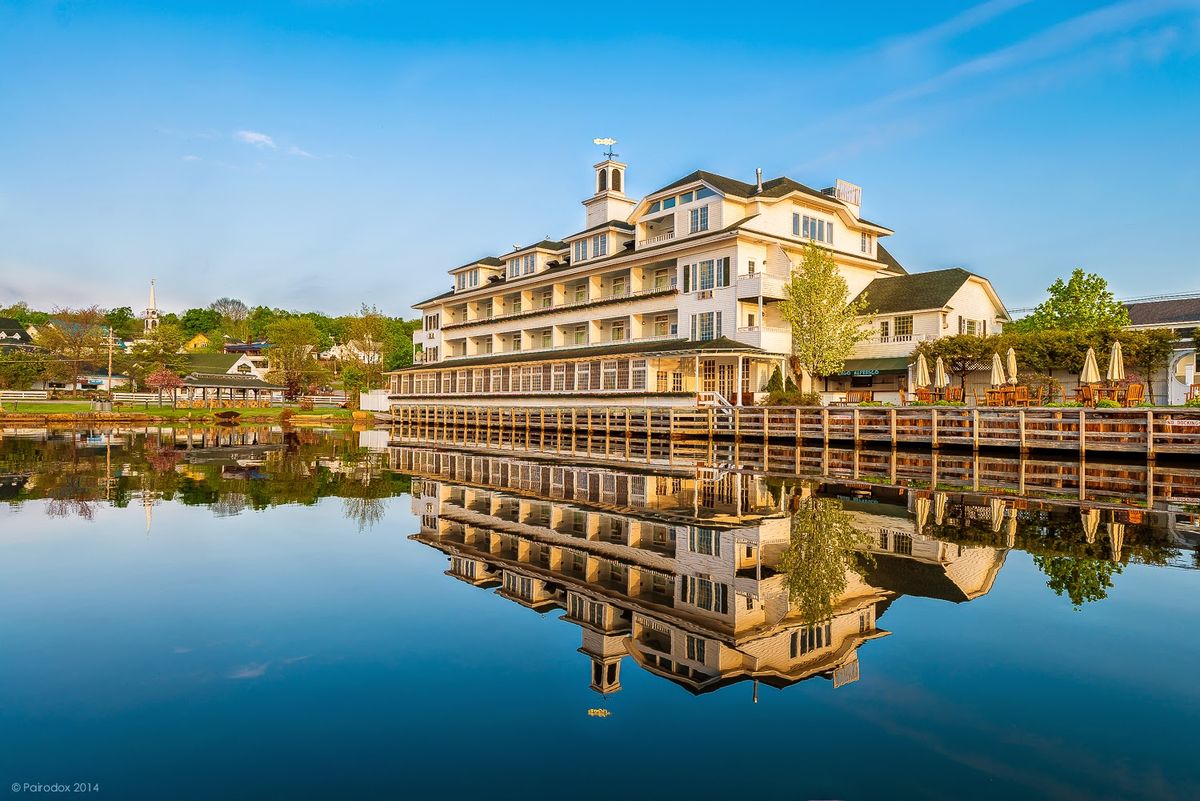Lake Winnipesaukee at dusk — pine-fringed islands and a wooden steamship dock, golden light over still water