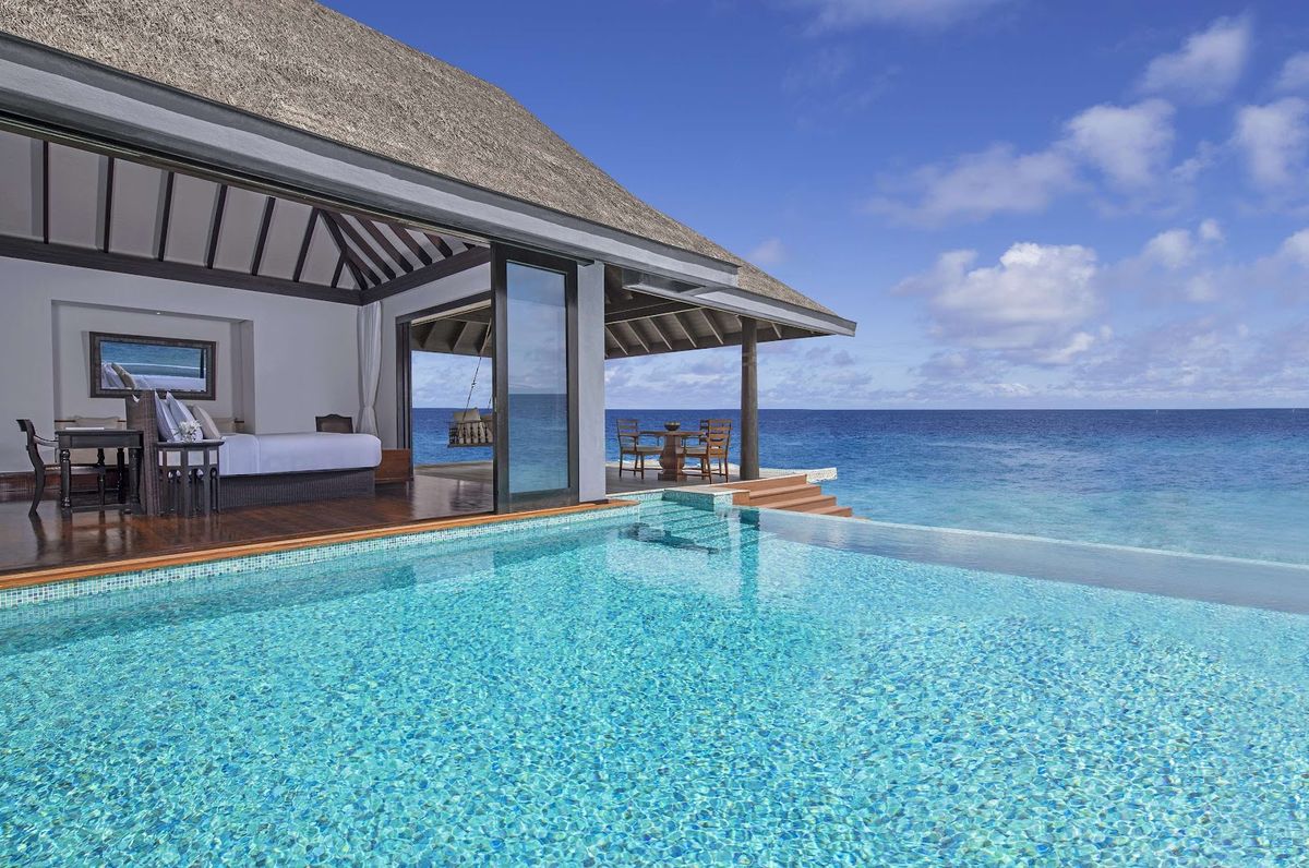 Maldives aerial view — overwater villas in coral lagoon with turquoise water and pristine white sand beach, Indian Ocean