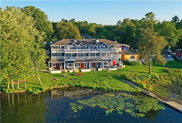 Muskoka cottage country — pine-fringed lake at sunset, Adirondack chairs on a granite shore in Ontario's lake district