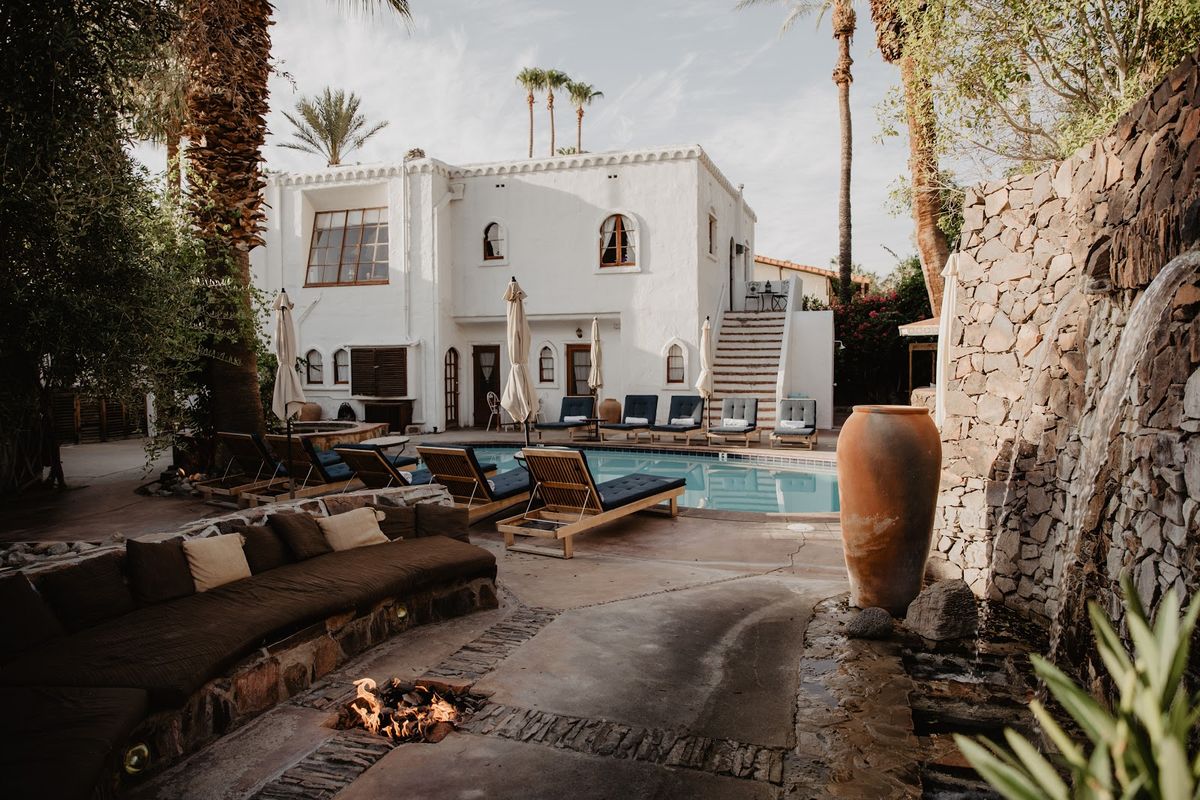 Palm Springs pool and palm trees against the San Jacinto Mountains — mid-century modern desert resort scene at golden hour