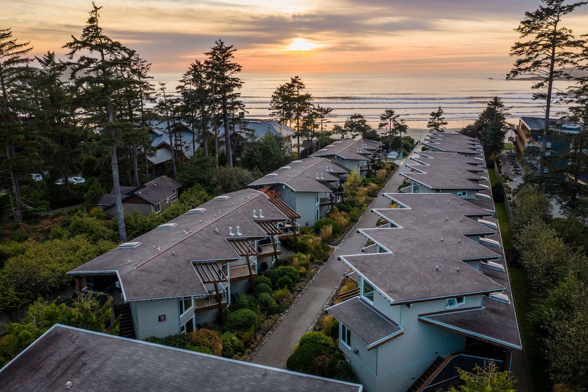 Tofino Pacific coast — surfer paddling out at sunset on Cox Bay